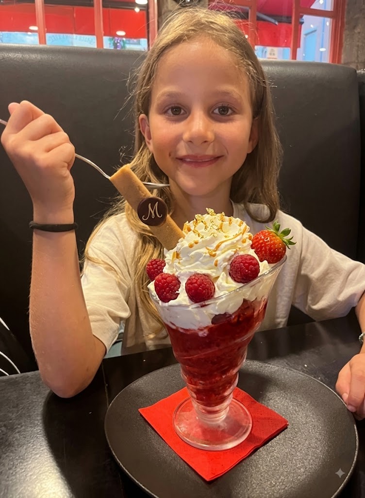 Jeune invitée souriante devant un dessert glacé aux fruits rouges