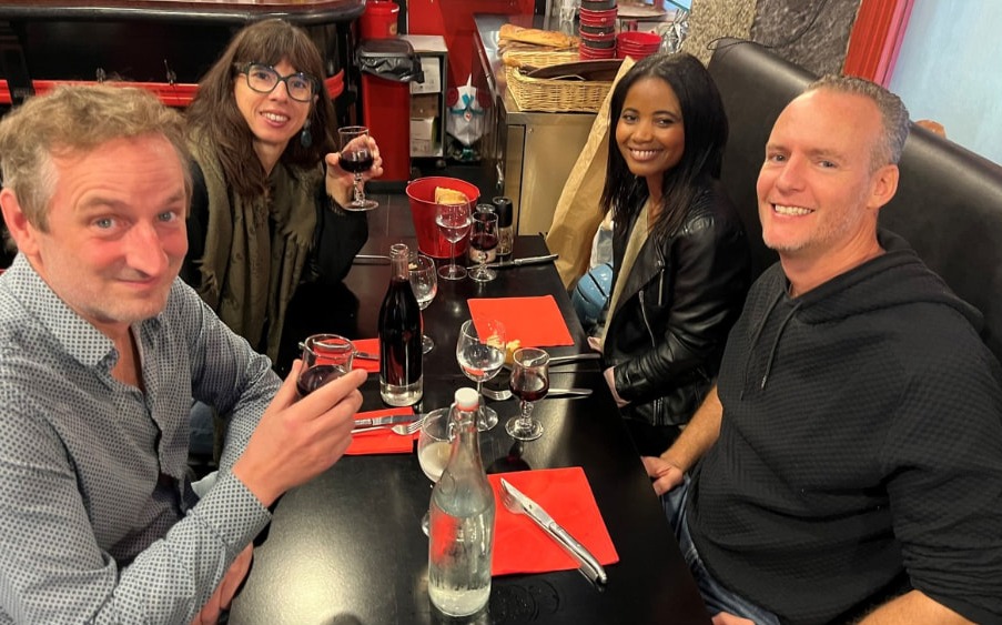 Deux couples attablés levant leur verre de vin rouge pour trinquer